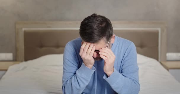 Un disperato uomo di mezza età che piange sul letto. Stressato maschio maturo togliersi gli occhiali e sfregamento viso mentre seduto sul letto e piangendo nella disperazione a casa — Video Stock