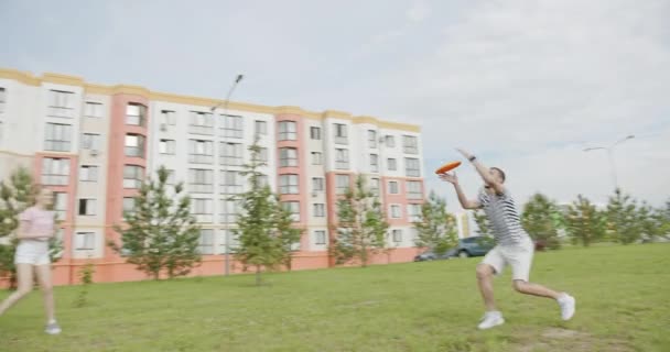 Dinamico tiro giovani amici trascorrono attivamente il tempo divertendosi a giocare a fly disc per strada vicino ai nuovi edifici moderni di case complesso residenziale — Video Stock