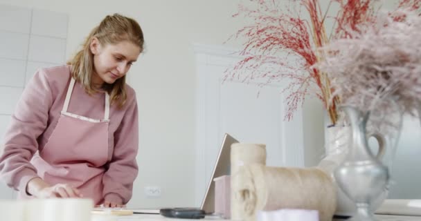 Młoda dziewczyna sklep właściciel kwiatów i prezentów działa na laptopie pisze zamówienie uśmiechając się stojąc za ladą jasny stylowy sklep — Wideo stockowe