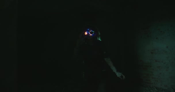 別の世界の少女、暗い中で輝く色の眼鏡を持つ未来のロボットは、超常現象を見るために放棄された老朽化した建物の上を歩く — ストック動画