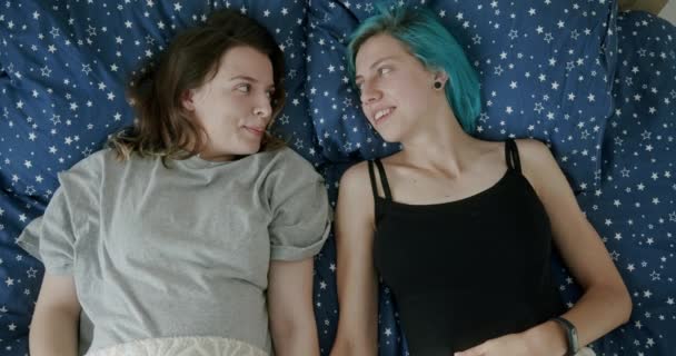 Jeune couple lesbien couché sur un lit regardant avec amour les uns les autres avec des expressions tendres dans une vue du haut vers le bas — Video