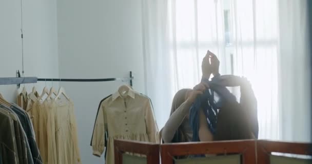 Молодая женщина дизайнер стильной одежды примеряет новую коллекцию белья платье в синем на модель в ее современной студии светлой моды — стоковое видео