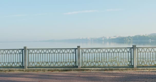 Een jong langharig meisje wandelt 's morgens bij het meer tegen de achtergrond van een prachtige blauwe lucht. — Stockvideo