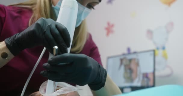 Maskeli genç doktor, en son tarayıcı teknolojisine sahip bir hastayı kliniğin diş muayenehanesinde oturan bir dizüstü bilgisayara video göndererek tedavi ediyor. — Stok video