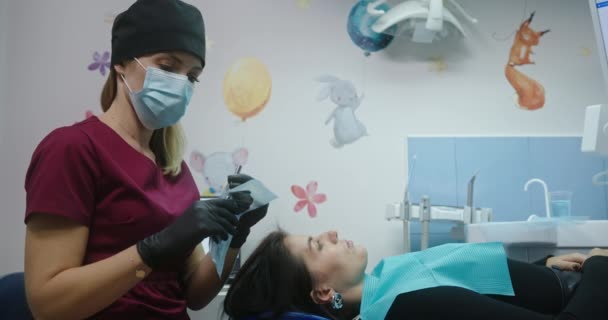 Aufnahme einer Patientin durch einen jungen Arzt Zahnarzt Kieferorthopädin Patientin liegt auf einem Zahnarztstuhl Ärztin untersucht ihre Zahnarztkonsultation — Stockvideo