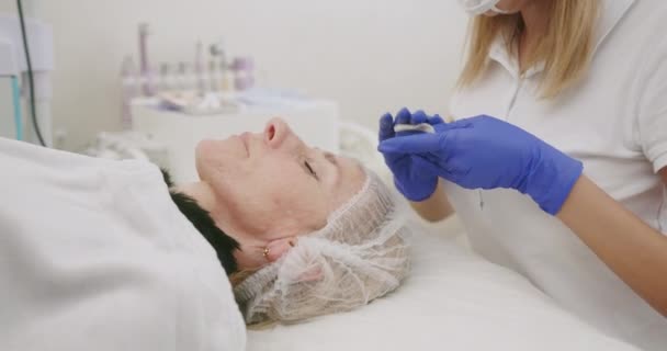 Žena kosmetik čištění obličeje klienta — Stock video