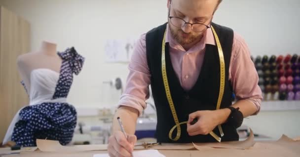 Krawiec robi pomiary i zapisuje notatki projektując indywidualną odzież — Wideo stockowe