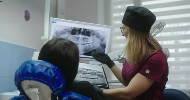 Dentista feminina mostrando raios-X dos dentes ao paciente — Vídeo de Stock