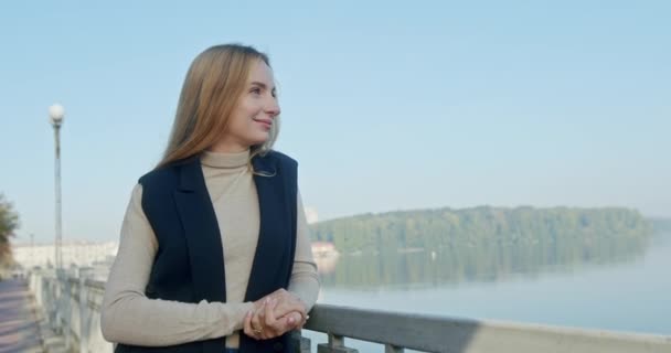 Young beautiful woman standing happy dreamy smiling outdoors on a sunny day on the lake promenade — Stock Video