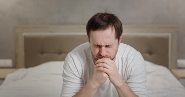Un hombre en un estado de depresión está pasando por un período difícil en la vida es apatía deprimida desesperación tristeza sentado en casa en la cama apoyado en sus manos su cabeza — Vídeos de Stock