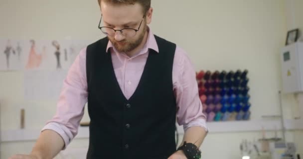 Męski projektant mody rysuje szkic nowej kolekcji środków odzieżowych o parametrach linijki centymetrów przyszłego produktu stojącego w warsztacie stojącym — Wideo stockowe