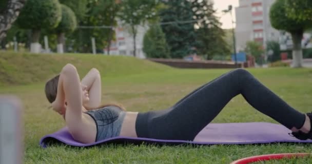 Oefeningen voor het pompen van de pers online workout video-opname op een smartphone jong mooi slank meisje gaat in voor sport buiten in sportkleding — Stockvideo