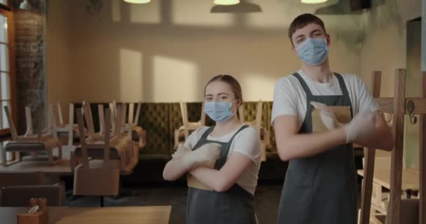 Dva číšníci chlap a dívka tvoří profesionální ruce s úsměvem při pohledu na sebe stojící v uzavřené restauraci, protože pandemie virus v maskách a rukavicích — Stock video