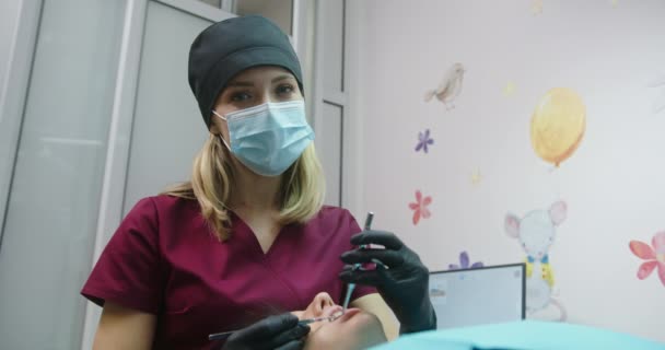 El proceso de tratamiento dental por una ortodoncista profesional médico dental mujer mirando a la cámara paciente sonriente sentado en una silla dental — Vídeos de Stock