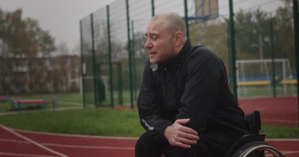 Behinderte Sportler Mann mit Behinderungen nicht funktionierende Beine Blick in die Kamera lächelnd zeigt Daumen nach oben Klasse sitzt im Rollstuhl auf Stadionstraße außerhalb — Stockvideo