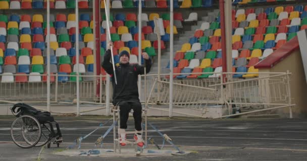 Lancio lancia allenamento atleta disabile uomo con gambe difettose seduto su una sedia a rotelle Esercizio per l'allenamento delle mani sulla strada fuori dallo stadio — Video Stock