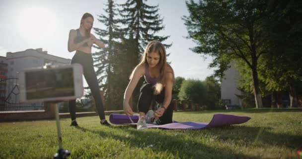 Jonge sportvrouwen die zich voorbereiden op online training in het park — Stockvideo
