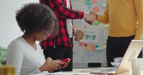 Due persone che si stringono la mano, una ragazza afroamericana nera seduta a correre a guardare il lavoro di squadra in ufficio sul tema dell'ecologia — Video Stock