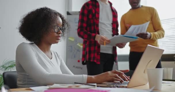 Scuro pelle afroamericana ragazza seduta in esecuzione guardando la fotocamera sorridente togliersi gli occhiali, Due persone in piedi sullo sfondo del lavoro di squadra in ufficio sul tema dell'ecologia — Video Stock