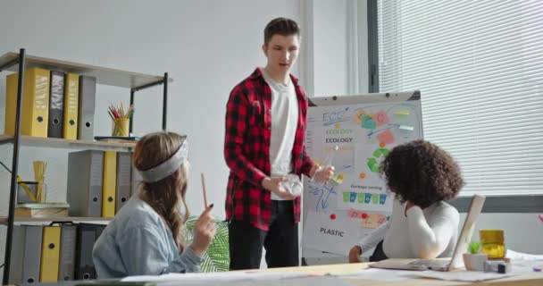 Egy csapat multiracionális fiatalember összehasonlítja a műanyagot és az üveget, hogy megoldja a környezeti problémákat az irodában. — Stock videók