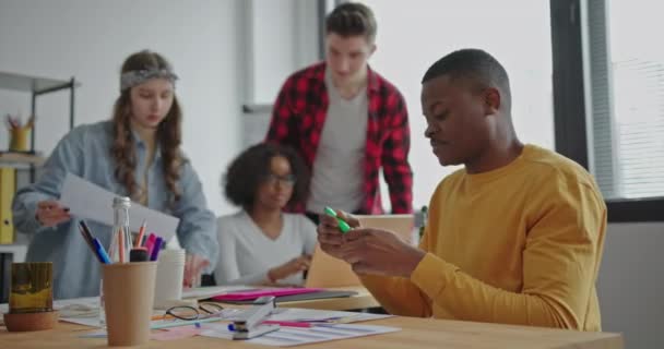 チームワークのプロセス多人種間アフリカ系アメリカ人活動的な若者は、テーブルに座っているオフィスで積極的に生態系の話のトピックを議論します。 — ストック動画