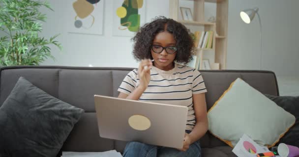 Young African American student using laptop on sofa — Stock Video