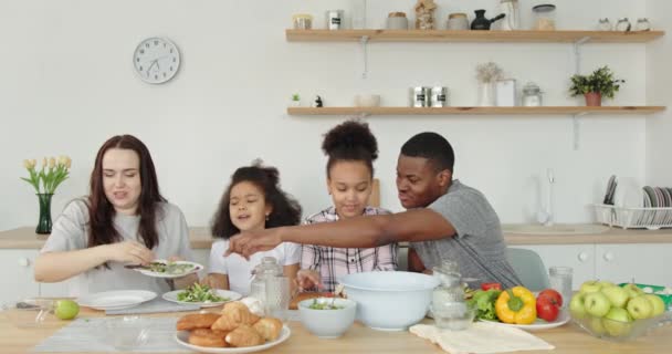 Мультиэтническая семья наслаждается временем вместе во время приготовления пищи на кухне — стоковое видео