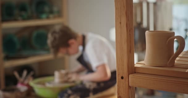 Młody nastolatek zajmuje się garncarstwem siedząc w kole garncarskim nie tworzy produktu, wybucha z awarii narzędzi ręcznych — Wideo stockowe