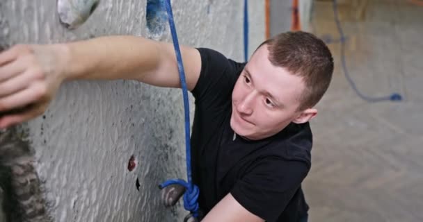 Mladík vyleze na umělou zeď studovat vyleze zeď v pojištění těžké překonat překážky fyzicky překonává lezení uvnitř — Stock video