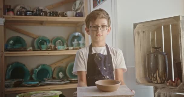 कार्यशाळामध्ये हाताने तयार केलेले चिकन बाऊल प्रदर्शित करणारा मुलगा — स्टॉक व्हिडिओ