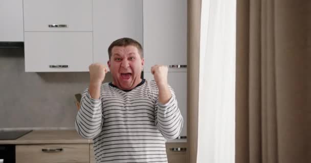 Izgatott férfi ünnepli a sikert a konyhában — Stock videók