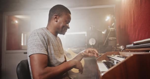 Чёрный человек играет на синтезаторе в студии звукозаписи — стоковое видео