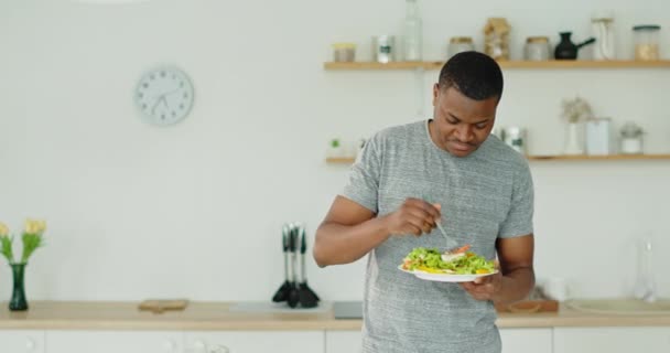 Hombre negro comiendo ensalada saludable en la cocina — Vídeos de Stock