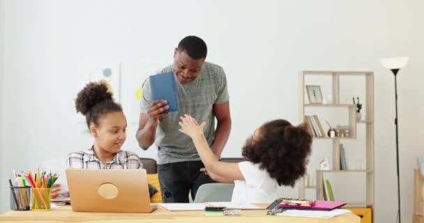 Padre negro mostrando libro interesante a las hijas durante la lección en casa — Vídeos de Stock