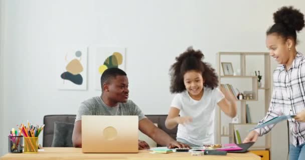 Happy girls przeszkadza pracy czarny ojciec w domu — Wideo stockowe