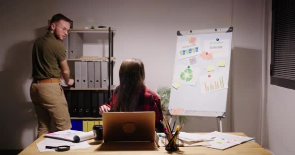 Femme travaille sur ordinateur portable à la table collègue cherche des documents — Video