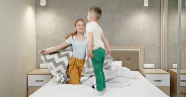 Bonito pouco menino saltos com irmã jogar no Grande macio cama — Vídeo de Stock