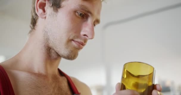 Jongeman kijkt naar elegant geel wijnglas in lichte kamer — Stockvideo