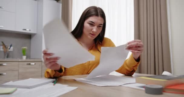 Эмоциональная женщина с ума от работы с бумагами сидит за столом — стоковое видео