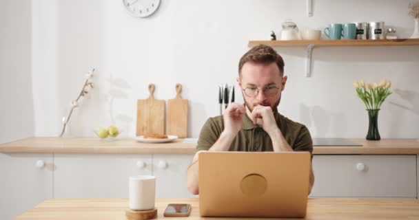 Pobożny człowiek patrzy na laptopa krzyżując palce w kuchni — Wideo stockowe