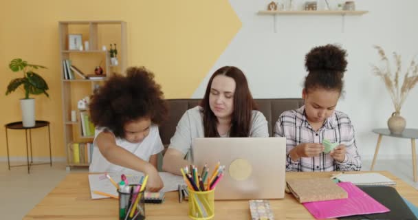 Multiracial familia blanca mamá enseña en línea a sus hijas afroamericanas negras sentadas en casa en el ordenador portátil escribir lecciones de abrazo y regocijo — Vídeos de Stock