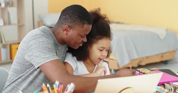 Att lära sig online kul leende positiva känslor ger fem svarta familj afro amerikansk pappa undervisar lektioner hemma med sin dotter sitter vid bordet och laptop — Stockvideo