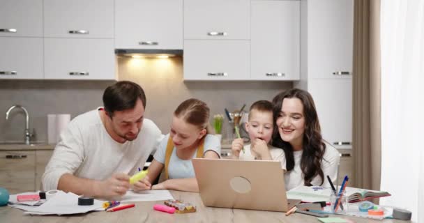 Boldog család anya és apa szülők tanulni gyerekek ülnek asztalnál otthon laptop fia és lánya ölelés mosolygós — Stock videók