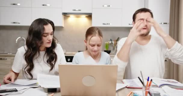 Сімейна мама і тато дочка сидять за столом вдома, вивчаючи онлайн роздратовані втомлені сумні кидають папери, дивлячись на голову на руки і втомившись — стокове відео