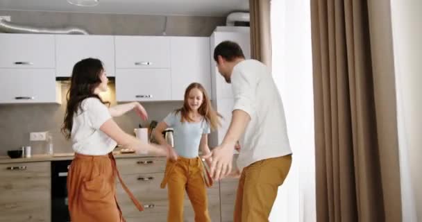 Happy family dance jumps on the background of modern apartment design konyha apa anya szülők és 2 gyermek fia és lánya aktív boldog — Stock videók