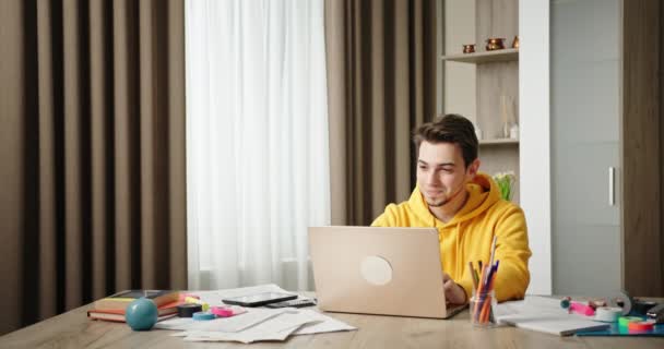 Młody facet pracujący w domu biuro siedzi przy biurku pracując na laptopie freelancer uśmiechając się pozytywnie pracując raduje się z sukcesu profesjonalny projekt — Wideo stockowe