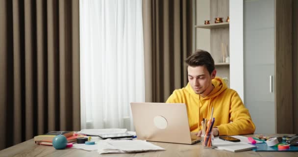 Розмова онлайн Молодий хлопець сидить вдома офіс сидить за столом, розмовляючи на ноутбуці посміхаючись позитивно махаючи привіт радіє сміється жарти — стокове відео