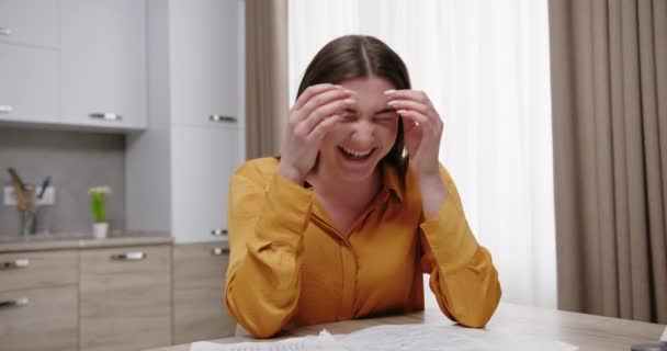 Tânăra femeie frumoasă râde emoțional emoții pozitive glume și râde stând la masă acasă într-un apartament luminos — Videoclip de stoc
