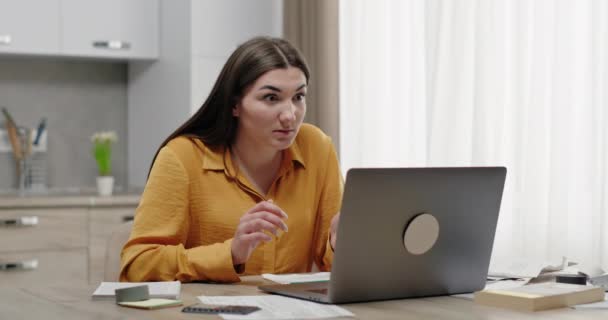 Frau, die zu Hause im Büro arbeitet, blickt überrascht auf Laptop empfindet unterlegene Entrüstung und Traurigkeit Scham hält Hände hinter dem Kopf am Tisch in der Wohnung sitzend — Stockvideo