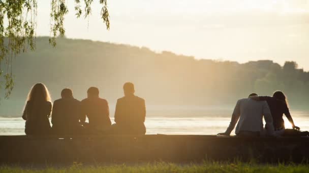 Les gens se détendent sur la plage au coucher du soleil — Video